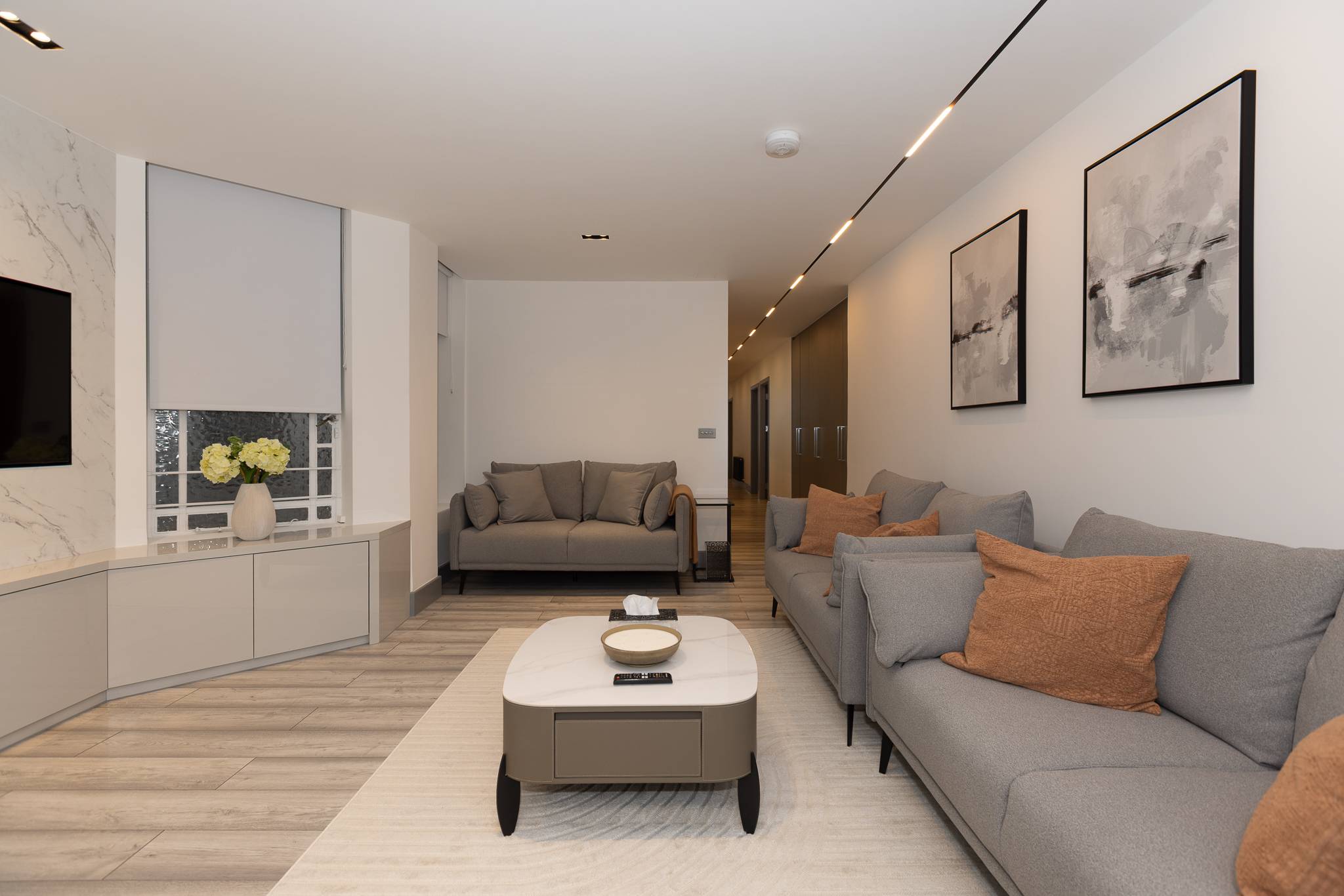 Second reception room with grey sofas, an oval coffee table and a marble clad window bay