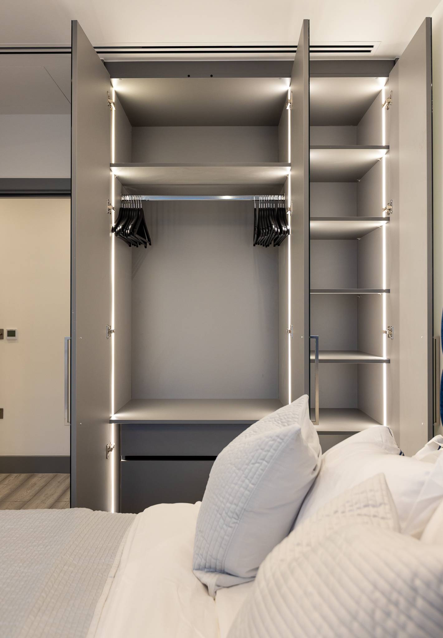 Open fitted wardrobe with LED strip lighting, hanging rails and adjustable shelves