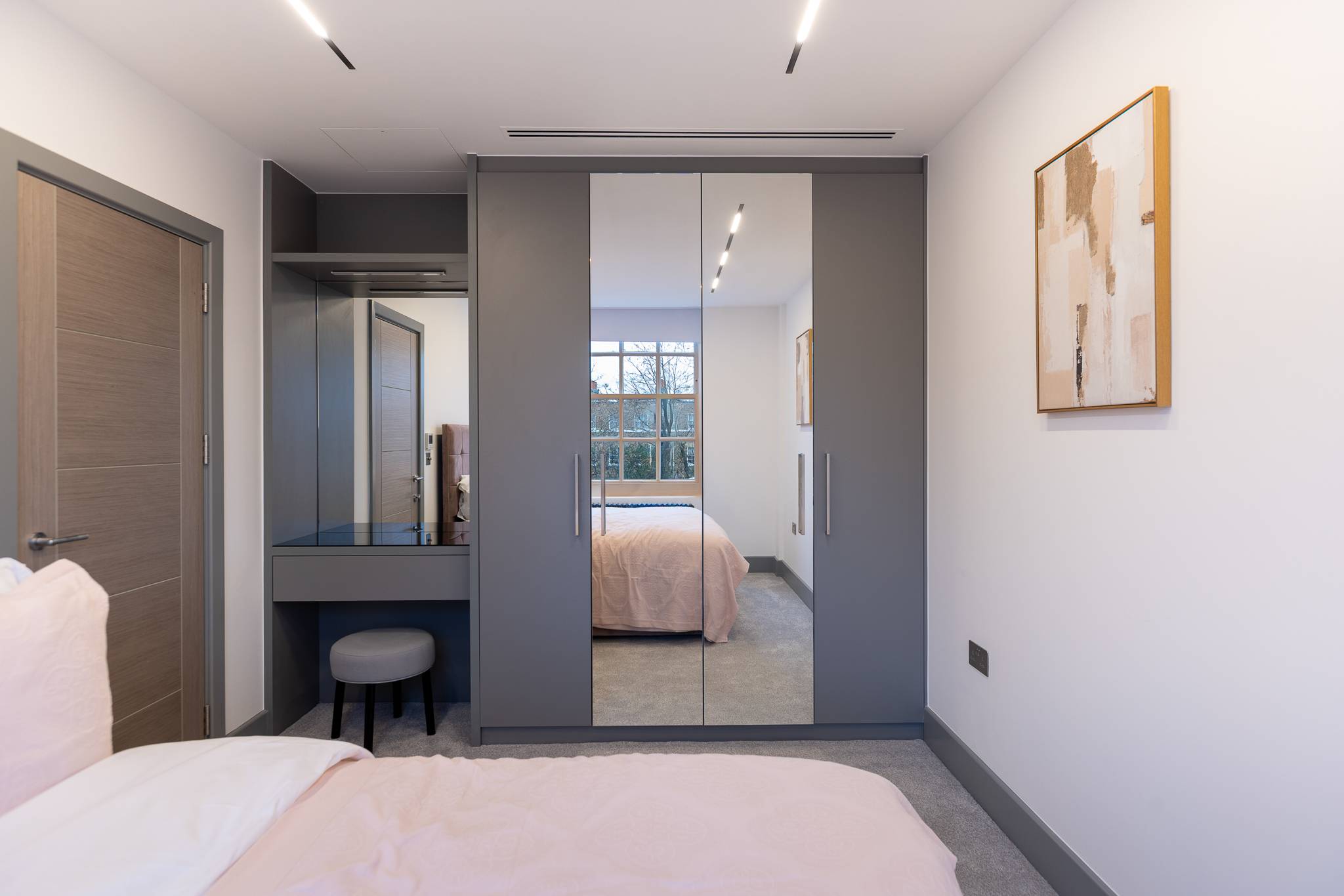 Bedroom with grey fitted wardrobes, a mirrored door and a built in dressing table