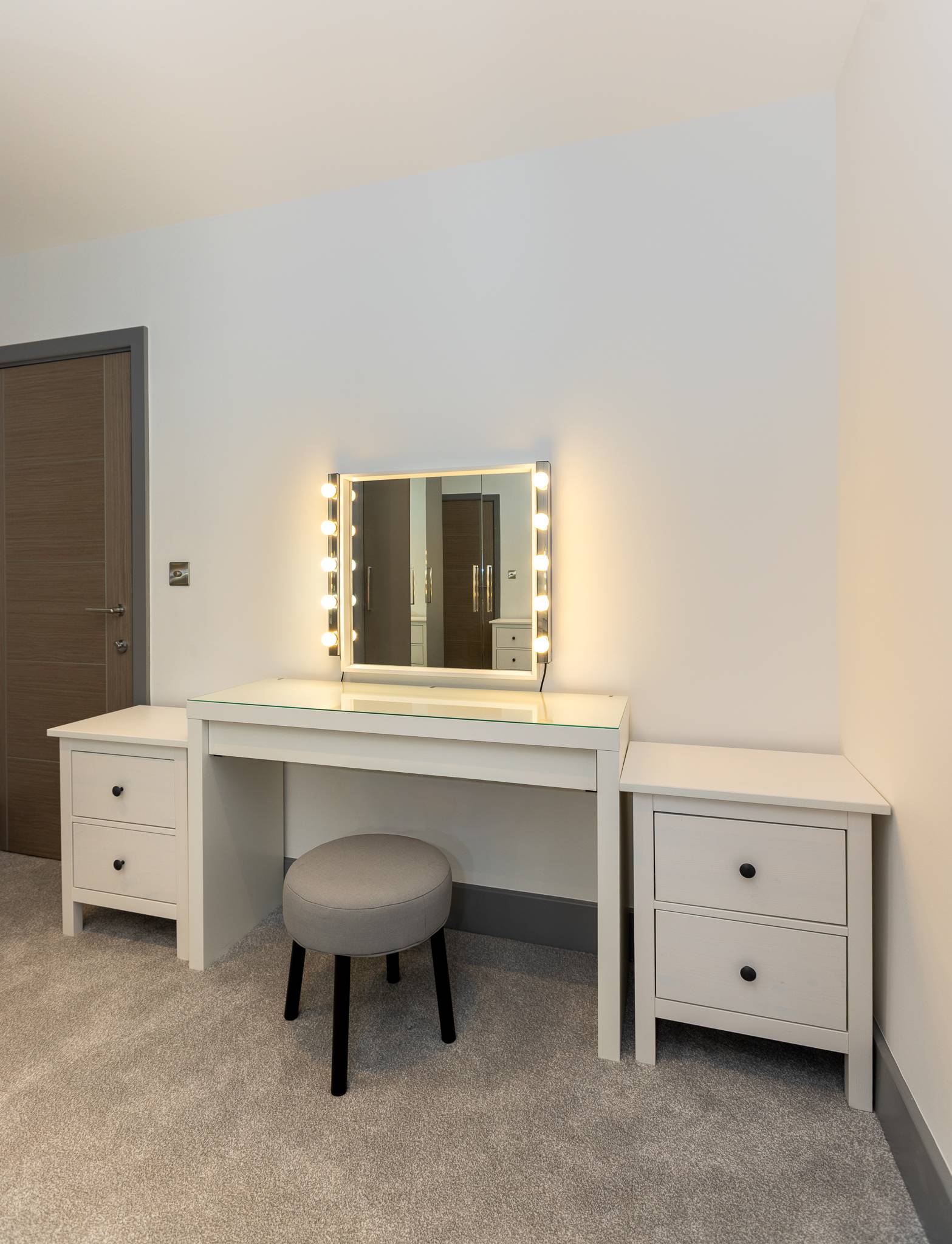 Dressing table with a lit Hollywood mirror and a grey velvet stool