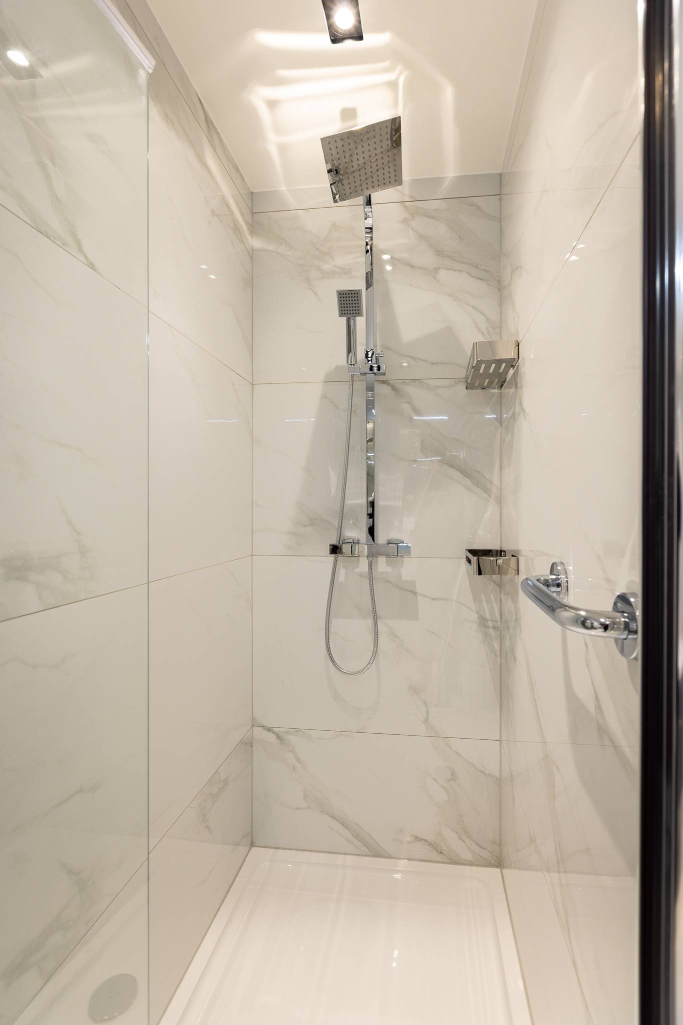 Walk in shower with a rainfall head, tiled floor to ceiling in white marble effect