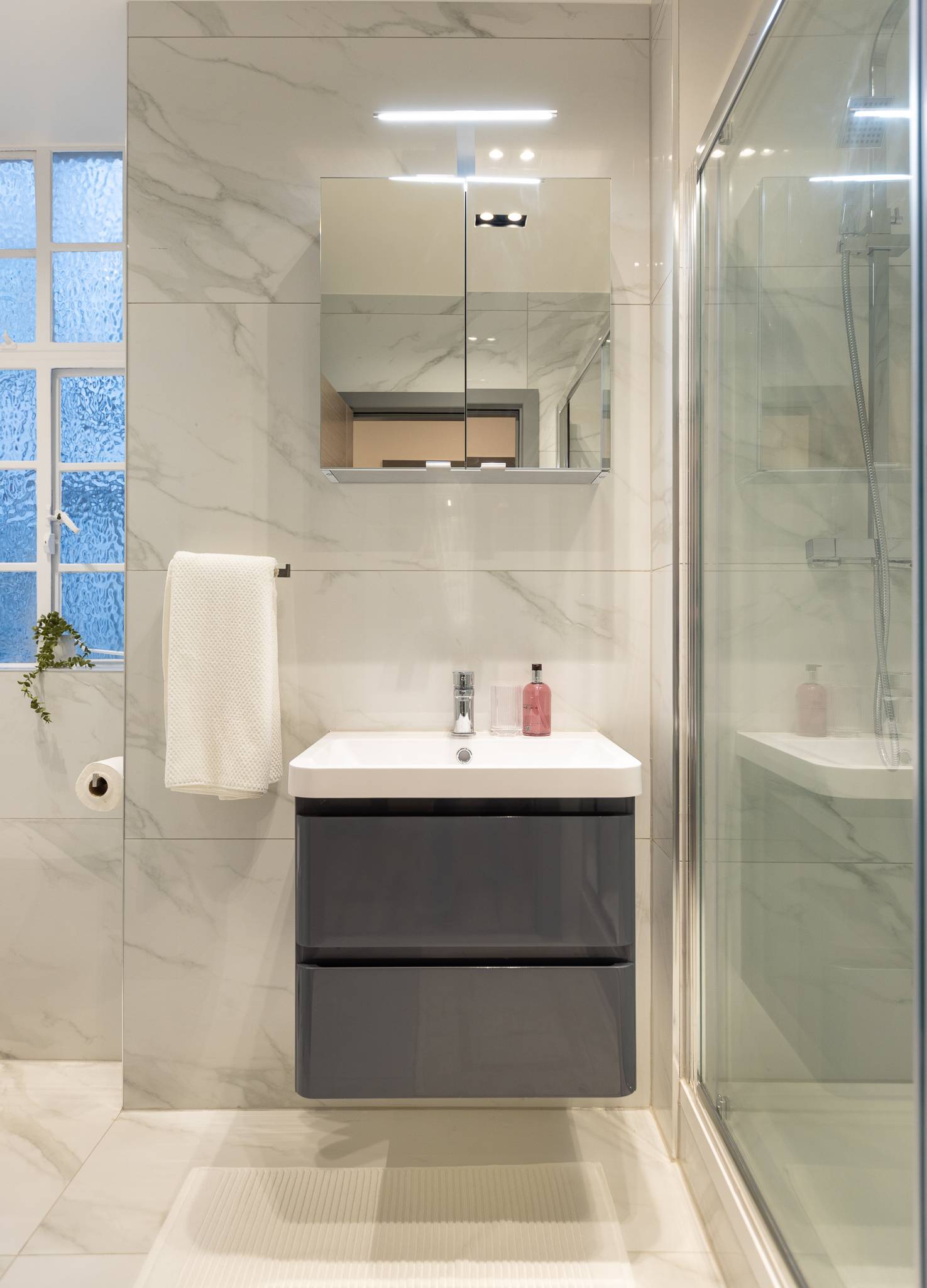 En suite with a glass shower enclosure, floating vanity and mirrored cabinet
