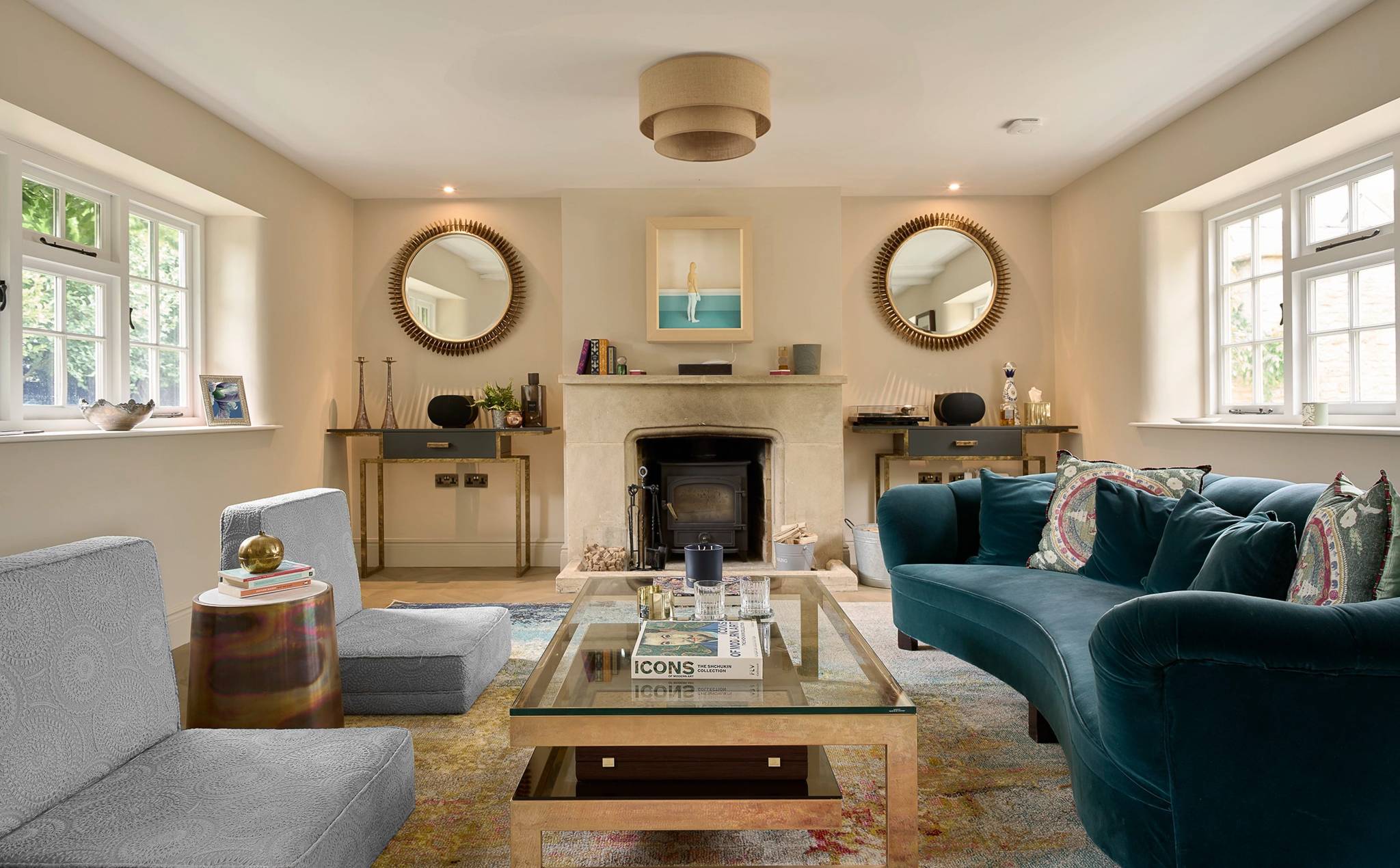 Living room of the Cotswolds country house refurbished by YPS, with a stone fireplace and teal velvet sofa