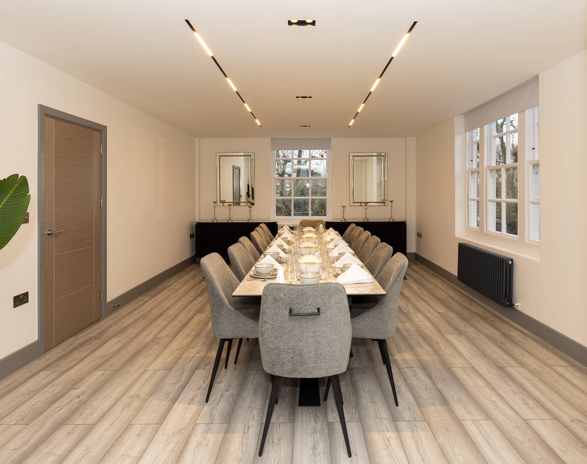 Dining room after the refurbishment, with a long dining table under linear lights in the new dropped ceiling